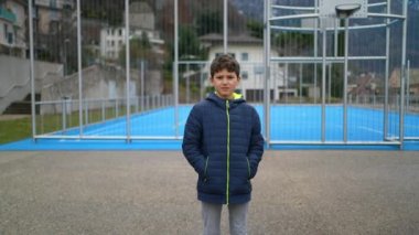 Dışarıda kameraya bakan ciddi bir gencin portresi. Ergen erkek çocuk kış mevsiminde parkta ciddi bir ifadeyle duruyor..