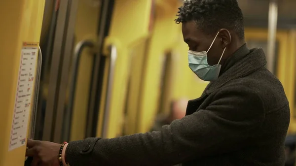 Commuter exiting subway wagon in underground metro wearing face mask