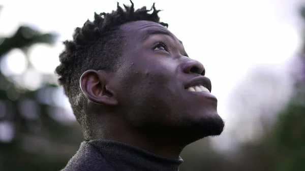 Close-up black man face looking up at sky smiling