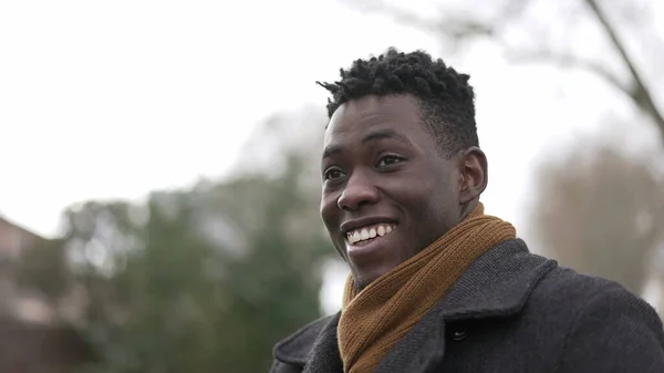 Charismatic happy black African young man smiling outside wearing scarf and winter coat