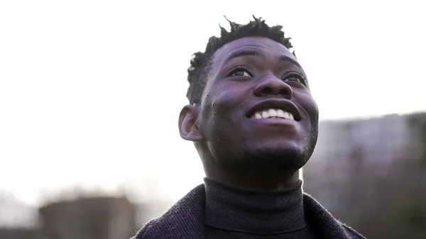 Close-up black man face looking up at sky smiling