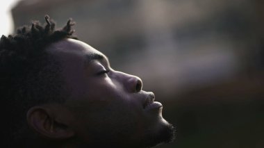 Meditative African man closing and opening eyes looking at sky smiling with FAITH and BELIEF