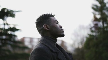 Umut dolu siyah adam gözlerini gökyüzüne açıyor gülümsüyor