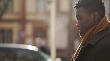 Düşünceli siyahi bir adam kış mevsiminde şehirde tek başına dolaşarak çekim yapıyor.
