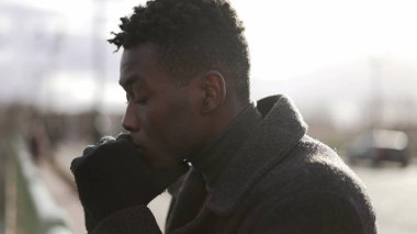 Düşünceli siyah Afrikalı adam köprünün yanında durup ufka bakan hayatı düşünüyor.