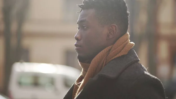 Pensive black man walking outside in city thinking by himself during winter season, tracking shot