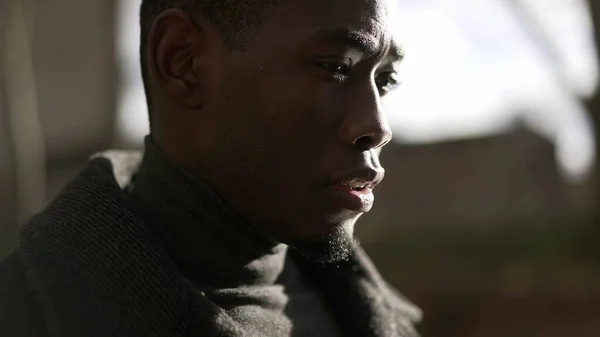 Pensive black man walking outdoors. Introspective pensive African guy thinking