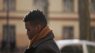 Düşünceli, düşünceli, Afrikalı bir adam kış mevsiminde dışarıda yürüyor.