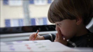 Hareket halindeki bir trende ev ödevi yaparken konsantre çocuk burun karıştırması.