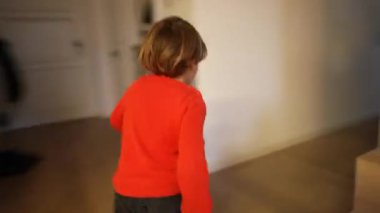 Modern oturma odasında koşan heyecanlı mutlu bir çocuk. Evin içinde koşan küçük bir çocuğun arkası. El bilgisayarı görüntüleri