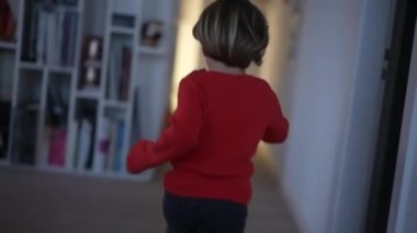 Modern bir evde koşan mutlu bir çocuk. Heyecanlı küçük çocuk ağır çekimde içerde koşuyor.
