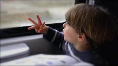 Trenin penceresinde oturan küçük bir çocuk buradan geçen manzaraya bakıyor. Hareket halindeki heyecanlı çocuk