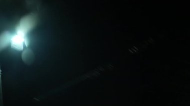 Arabadaki yolcuların gece lamba direklerine bakışları bulanık bir bakış açısı. Kirli parçacıklarla karanlıkta parlayan ışık