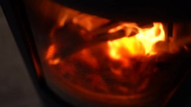 Odunların yakıldığı yakın çekim. Şöminenin içindeki makro alevler cam yansımanın arkasında.