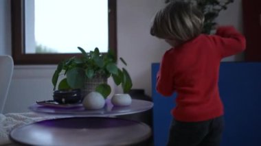 Modern oturma odasında koşan heyecanlı mutlu bir çocuk. Evin içinde koşan küçük bir çocuğun arkası. El kamerası görüntüleri yavaş çekimde