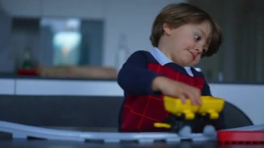 Küçük çocuk evde tren oyuncağıyla oynuyor. 2 yaşındaki sevimli bir çocuk, oturma odasındaki masada demiryolu hediyesiyle tek başına oynuyor.