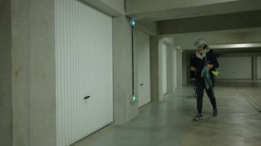Anne, çocuk bisikletiyle yeraltı garajını açıyor. Ebeveyn ve çocuk hafta sonu etkinliğine hazırlanıyor.