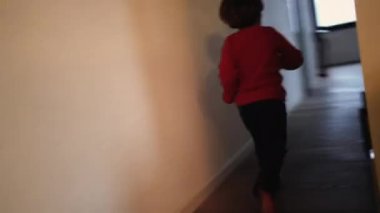 Modern oturma odasında koşan heyecanlı mutlu bir çocuk. Evin içinde koşan küçük bir çocuğun arkası. El bilgisayarı görüntüleri