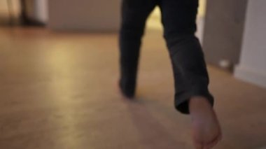 Evin içinde koşan aktif bir çocuk ayağı. Yakın çekim heyecanlı çocuk koşucu oturma odasında
