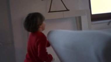 Oturma odasında koşan küçük çocuk. Aktif çocuk koşucusu eğleniyor ve kameradan kaçıyor. El bilgisayarı görüntüleri