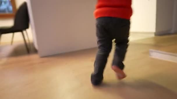 自宅のリビングルームで屋内で走る幸せな子供 近代的な家の中で子供の足のランナーを閉じます 手持ちの映像 — ストック動画