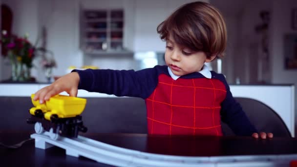 2歳の少年はおもちゃの贈り物で遊ぶ 新しいクリスマスプレゼントで遊ぶ子供 黄色のワゴンオブジェクトを保持赤いセーターを着て子供 — ストック動画