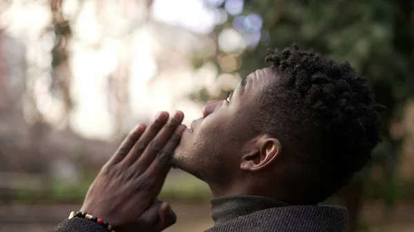 Religious young black man praying to God. African person looking up at sky with HOPE and FAITH