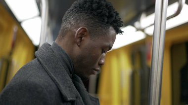 Genç siyah adam güneşli bir yolda metro ile gidip geliyor.