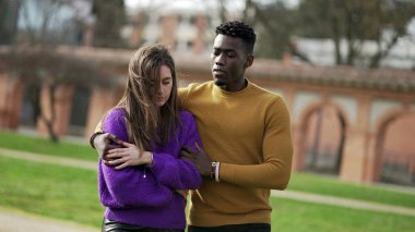 Erkek arkadaş kız arkadaşı teselli ediyor. Farklı ırklardan çiftler birlikte yürüyorlar.