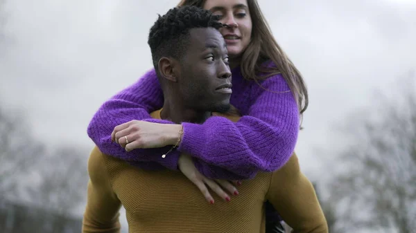 Boyfriend carrying girlfriend in back. Young millennial interracial couple, girl in man back