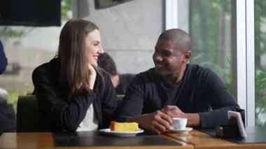 Kahve dükkanında oturmuş gülen ve gülümseyen mutlu çift. Kafe restoranında randevuda iki kişi.