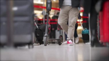 Kalabalık bir yerde elektrikli scooter taşıyan biri. Ulaşım ekipmanlı bir adamın düşük açılı klipsi