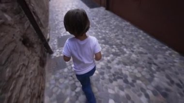 Küçük mutlu bir çocuk İtalya sokaklarında Avrupa kaldırımlarında koşuyor. Yukarıdan görülen çocuk koşucu
