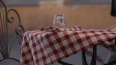 Milliken Masa Çarşafları Kontrol Noktası masa örtüsü rüzgarda süzülüyor. Şehir caddesinde boş bir restoran.
