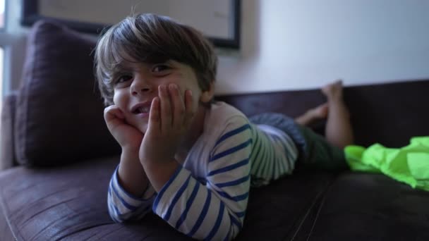 ソファに横になって顎を持つかわいい男の子の肖像画 ハンサムな子供の顔を閉じる自宅でリラックス — ストック動画