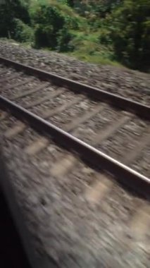 Tren rayları yüksek hızda hareket ediyor. Pencereden görülüyor. Dikey Videoda Yolcu POV