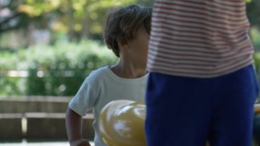 Çocuk atlıkarıncayı itiyor. Çocuk şehir parkında eğleniyor.