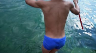 Çocuğun sırtı suya düştü. Küçük bir çocuk yavaş çekimde göle atlıyor. Mutlu çocuk yaz tatillerinin tadını çıkarıyor.