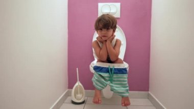 Tuvalette oturup ihtiyaçlarını gideren sevimli küçük bir çocuk.