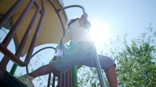아이는 공원의 놀이터 막대기에서 미끄러져 내려갑니다 활동적 어린이가 섬광등을 미끄러지는 — 비디오