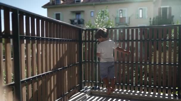 Uma Criança Brincalhona Varanda Apartamento Olhando Através Proteção Cerca Madeira — Vídeo de Stock