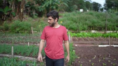 Genç adam küçük bir çiftlikte yürüyor. Mutlu insan çiftlikte gülümsüyor.