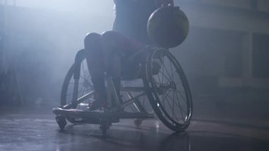 Etkileyici ışıklandırması olan tekerlekli sandalyedeki engelli basketbolcu. Özürlü bir atlet.