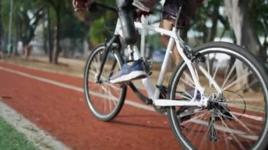 Dışarıda protez bacak kullanan engelli biri bisiklet sürüyor.