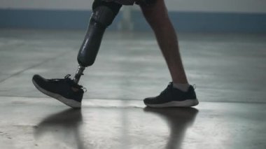 Kapalı alanda protez bacağıyla yürüyen engelli biri. Ampüte adam protez bacakla yürür.
