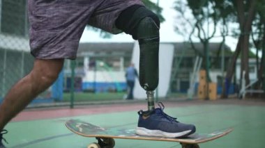 Protez bacağı olan engelli biri kaykay kullanıyor. Atletik kaykaycı ampüte