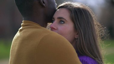 Genç milenyum ilişkisi. Siyah adam beyaz kız arkadaşına sarılıyor ve sarılıyor.