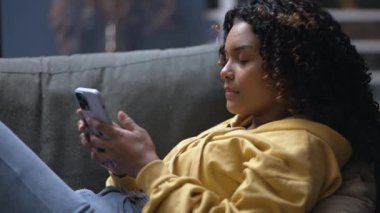 Sinirli genç siyahi bir kadın cep telefonunu kaldırıyor ve sosyal medyaya mesaj gönderiyor.