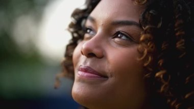 Umutlu genç siyahi kadın gülümseyerek gözlerini gökyüzüne açıyor. Minnettar mutlu Afro-Amerikan Latin 20 'li yaşlardaki kız. İnançlı düşünceli duygu..