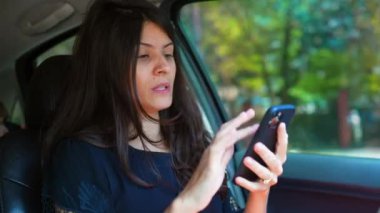 Arabadaki akıllı telefon cihazına bakan bir kadın. Sürücü trafikte sıkıştığında harita yönlerini kontrol ediyor. Kişi navigasyonu kontrol ediyor